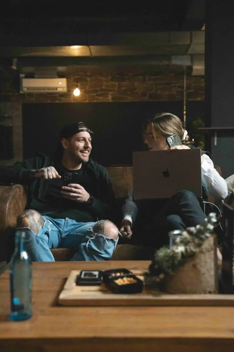Zwei Personen sitzen entspannt auf einer Couch in der PIKASS Lounge, mit Laptop und Smartphone, bereit zum mobilen Arbeiten.
