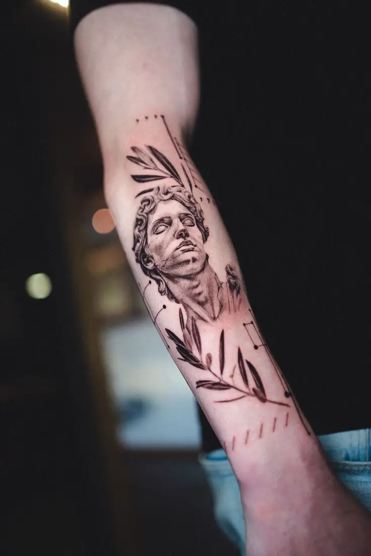 Black and Grey Tattoo auf dem Unterarm mit klassischem Statuenmotiv, Olivenzweigen und feinen geometrischen Linien