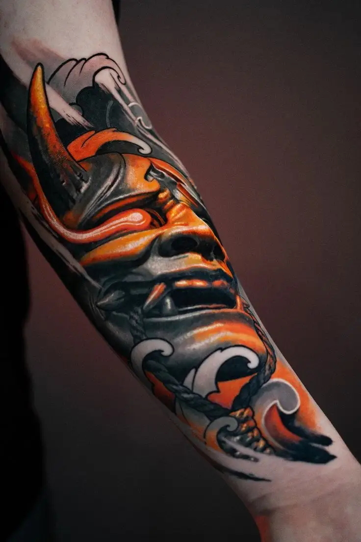 Farbiges Tattoo am Unterarm mit japanischer Hannya-Maske, Wellen-Elementen und kräftigen Orange-Schwarz-Kontrasten