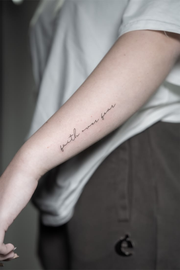 Feines Lettering Tattoo auf dem Unterarm mit dem Schriftzug faith over fear