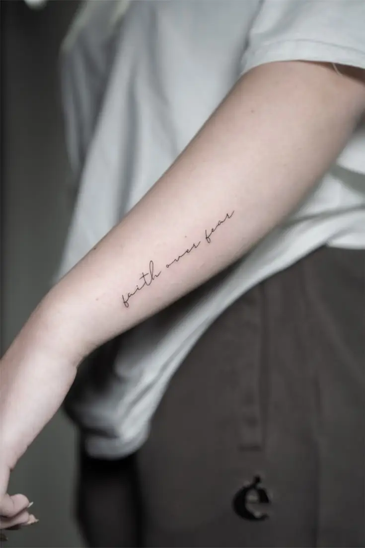 Feines Lettering Tattoo auf dem Unterarm mit dem Schriftzug faith over fear