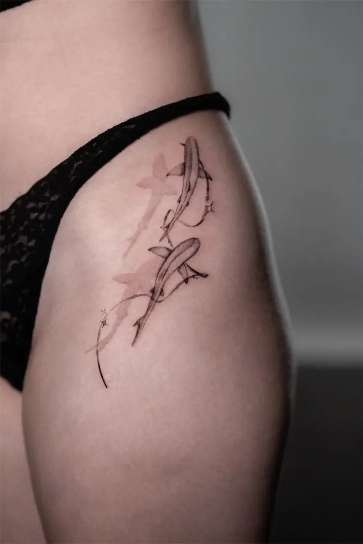 Feines Fineline Tattoo an Hüfte und Oberschenkel mit zwei Haien, zarten Linien und dezenten Farbakzenten