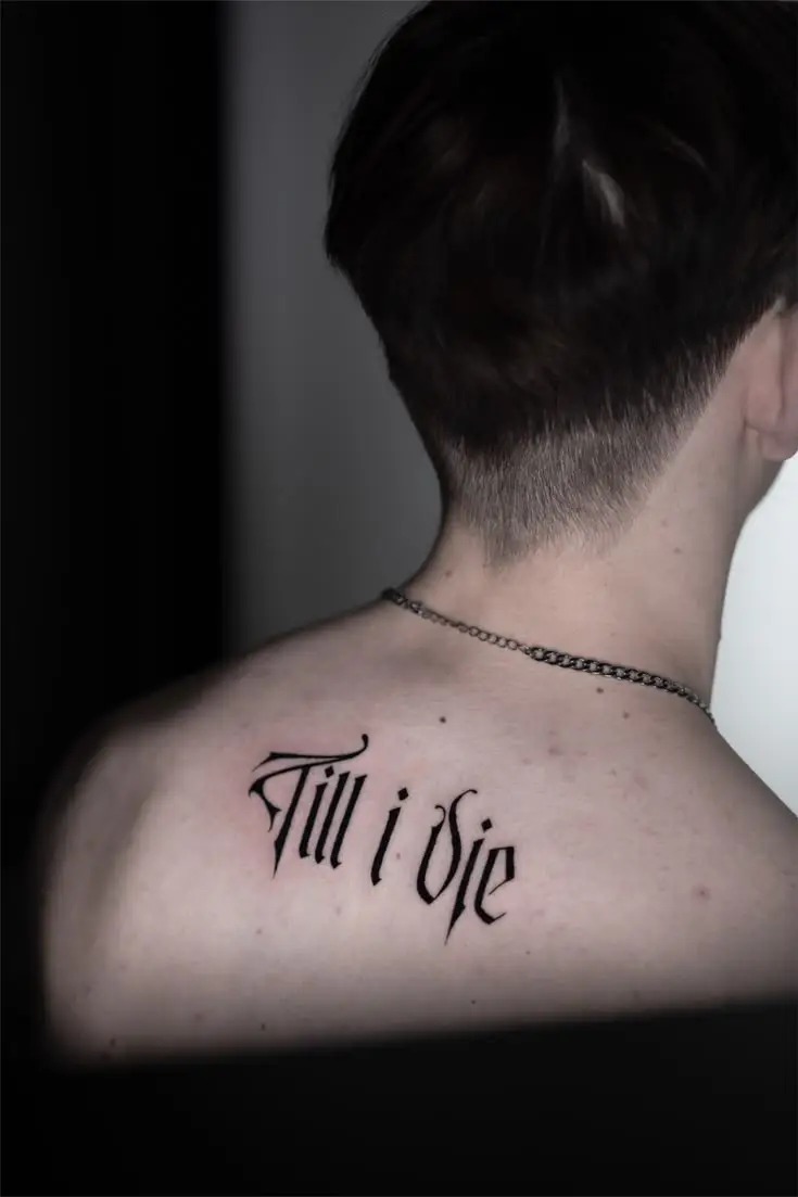 Lettering Tattoo auf dem oberen Rücken mit dem Schriftzug Till i Die in dunkler Gothic-Schrift