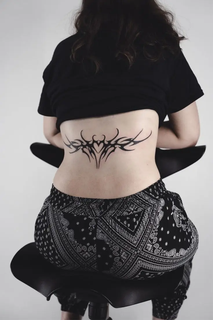 Symmetrisches Blackwork- und Graphic Tattoo im Tribal-Stil am unteren Rücken, gestochen von Manuel bei PIKASS TATTOO.