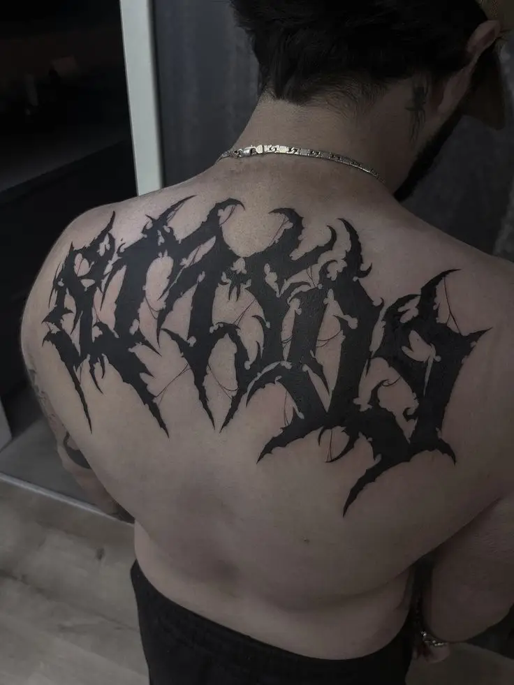 Großflächiges Blackwork- und Lettering-Tattoo als Schriftzug auf dem oberen Rücken, gestochen von Manuel bei PIKASS TATTOO.