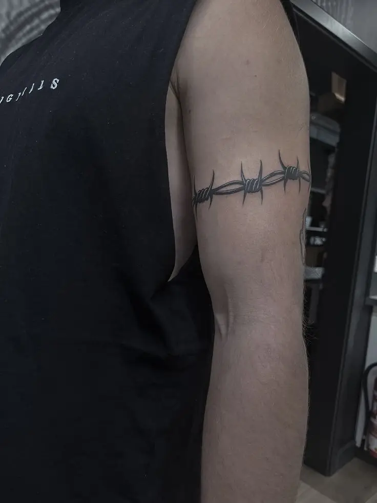Stacheldraht Tattoo im Linework- und Blackwork-Stil als Oberarm-Armband, gestochen von Manuel bei PIKASS TATTOO.
