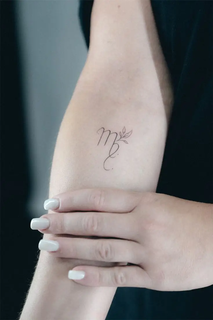 Kleines Fineline-Tattoo mit geschwungenem Sternzeichen-Symbol und Blättern am Arm