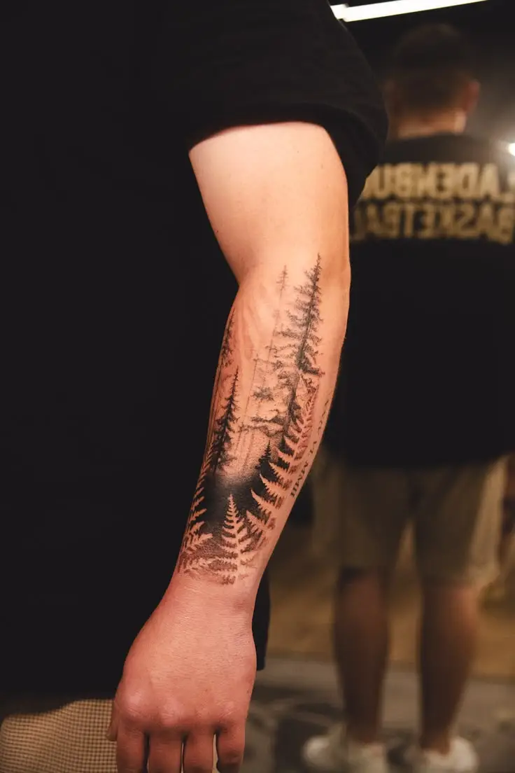 Feines Black and Grey Wald-Tattoo mit Tannen am Unterarm von Hanna